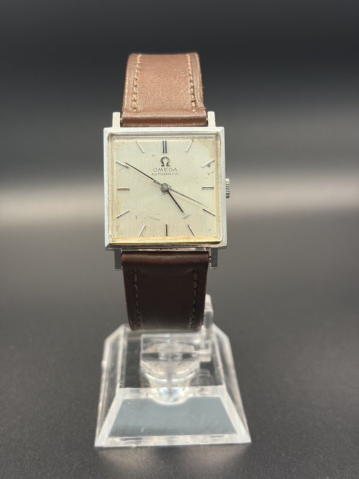 Vintage Omega Automatic square watch on a brown leather strap, front view on a stand