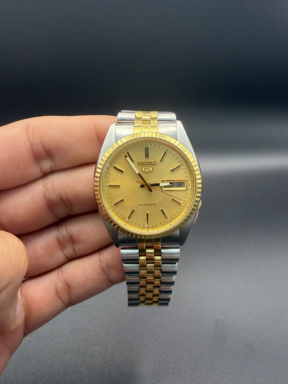 Seiko 5 automatic with gold dial, held in hand
