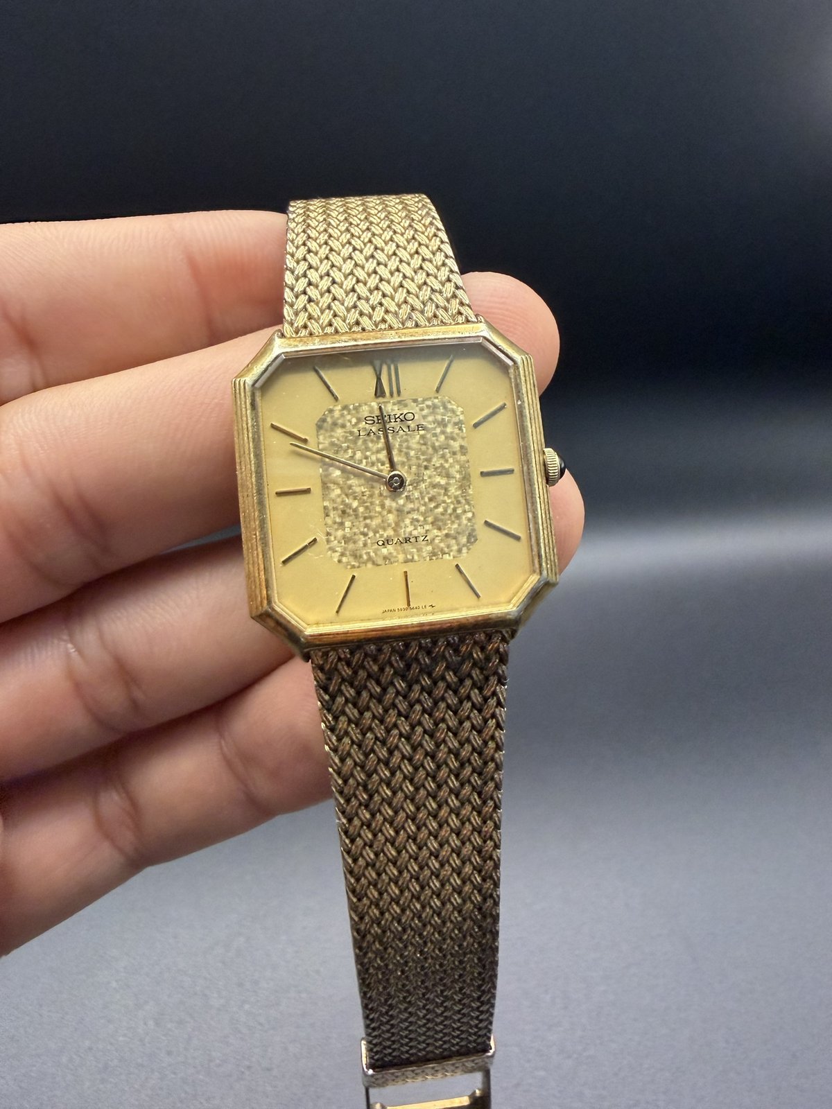 Seiko Lassale gold-tone watch on a woven mesh bracelet, held in hand